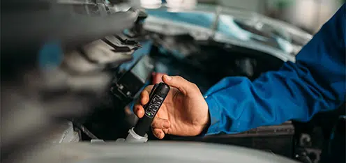 Mecánico de azul revisando el líquido de frenos de un auto